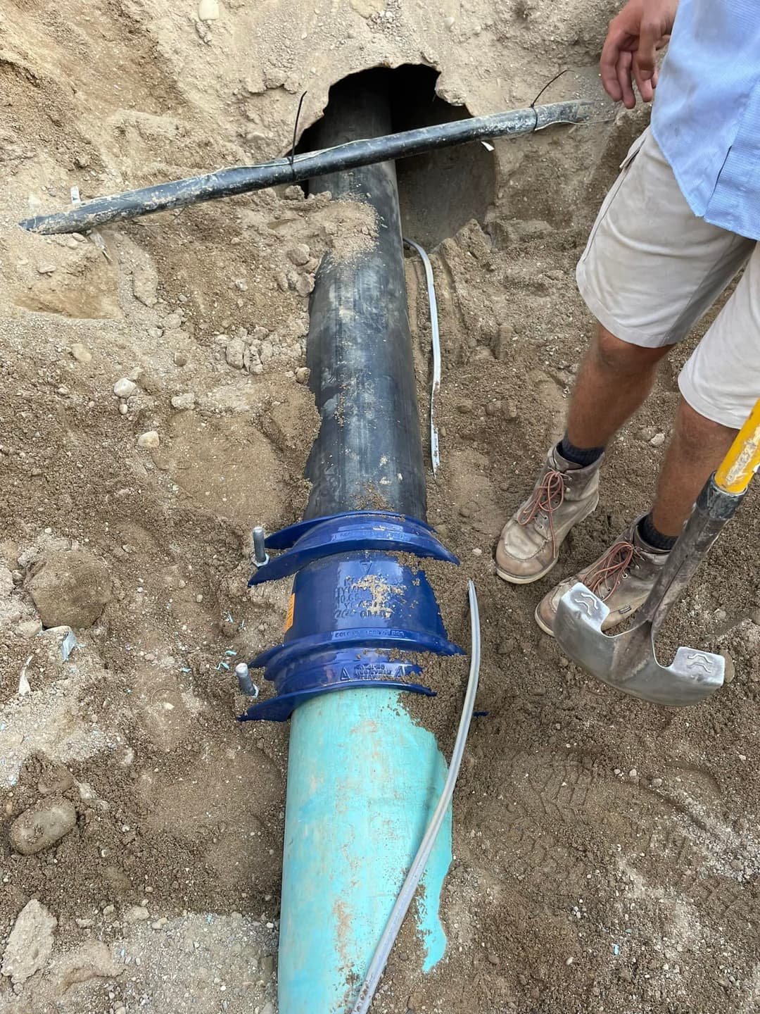 Maintenance crew repairing a water pipeline with tools near an excavation site.